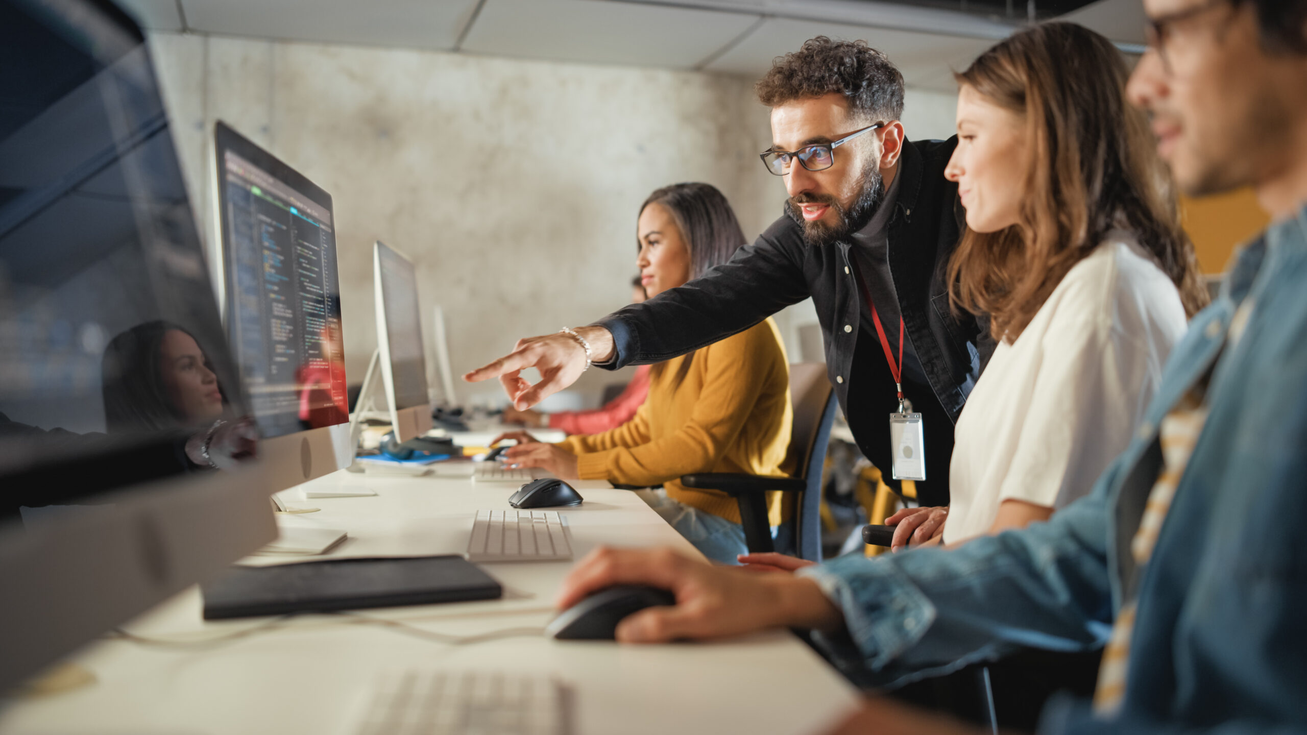 Jeune alternant et directeur artistique senior examinant ensemble des maquettes graphiques dans une agence de communication moderne